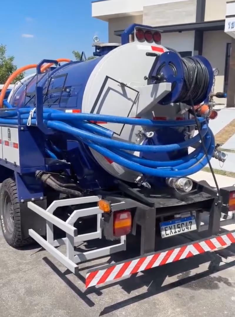 Caminhão tanque azul com mangueiras azuis e laranja enroladas na parte traseira.